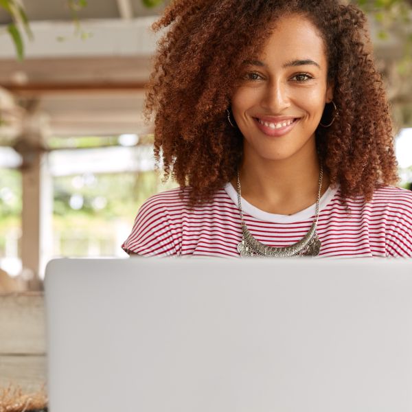 Junge Frau sitzt in Outdoorumgebung vor dem Laptop